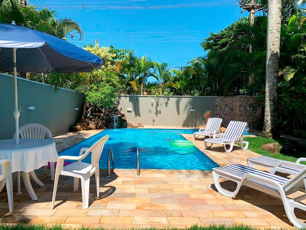 una piscina con sedie, tavolo e ombrellone di Incrivel casa a 13 min a pe da Praia de Juquehy SP a São Sebastião