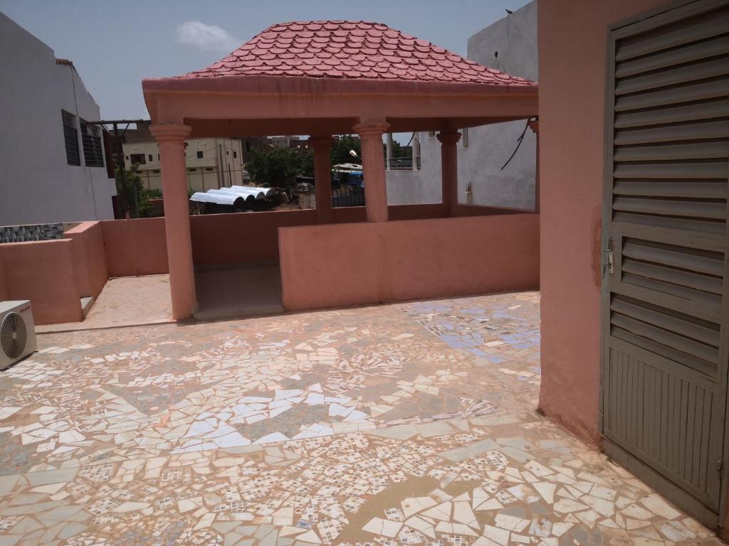 a gazebo on the side of a building with a tile floor at Résidence Les Fleurettes in Bamako
