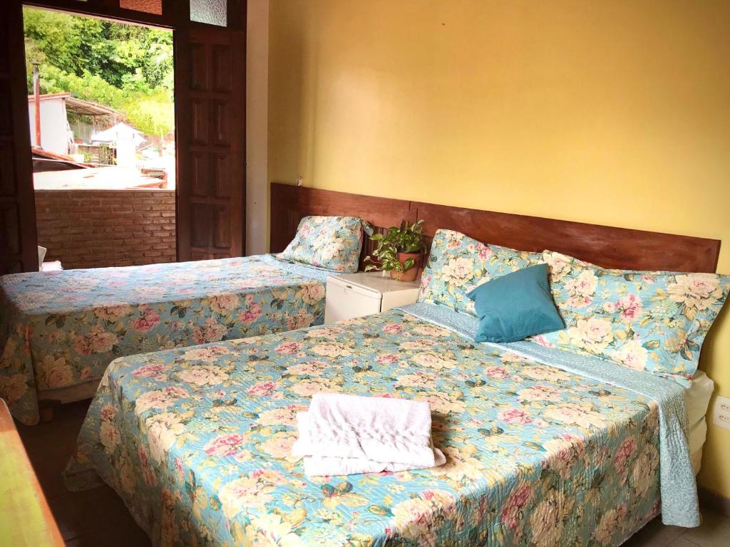 a bedroom with two beds with blue pillows at Pousada Morro Bello in Morro de São Paulo