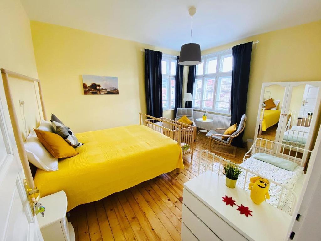 a bedroom with a yellow bed and a living room at TÁNIN HOUSE - Three-bedroom apartment, sauna and gym 10' away from Borovets in Samokov