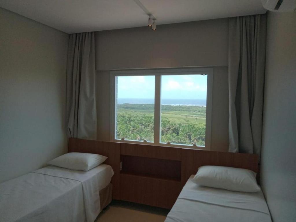 a room with two beds and a large window at Salinas Exclusive Resort 24 in Salinópolis