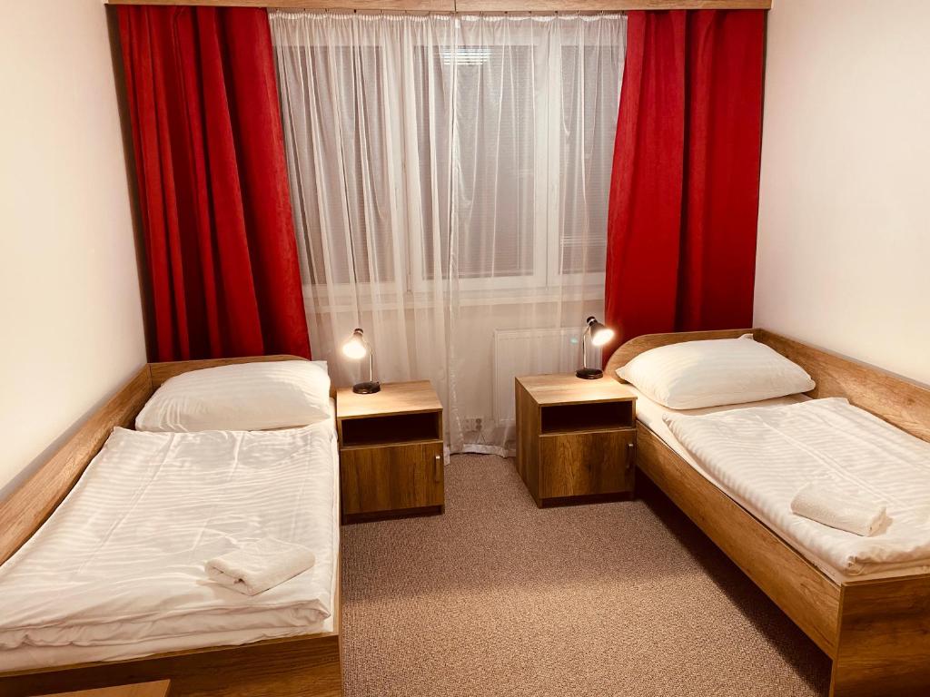two beds in a small room with red curtains at LC - Hotel Ostrava in Ostrava