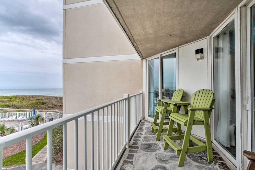 uma varanda com duas cadeiras verdes e o oceano em Colorful Beachfront Condo with Resort Amenities em North Topsail Beach