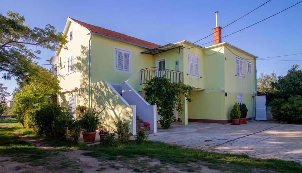 ein gelbes und weißes Haus mit Auffahrt in der Unterkunft Apartments Mir - family apartments with garden terrace in Zaton