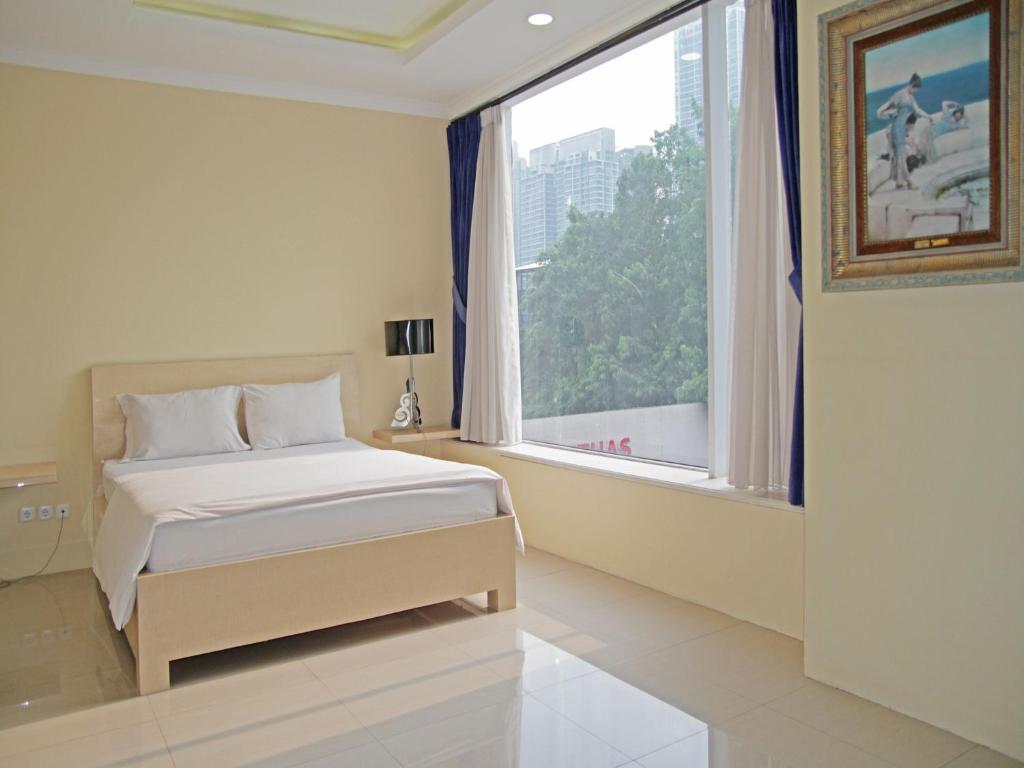 ein Schlafzimmer mit einem Bett und einem großen Fenster in der Unterkunft Kemang Eleven in Jakarta