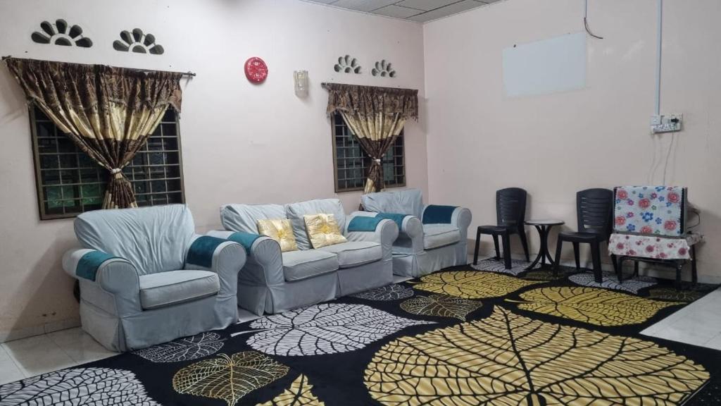 uma sala de estar com sofás e cadeiras num tapete em INAP DESA ABYKAMSHAR em Merlimau