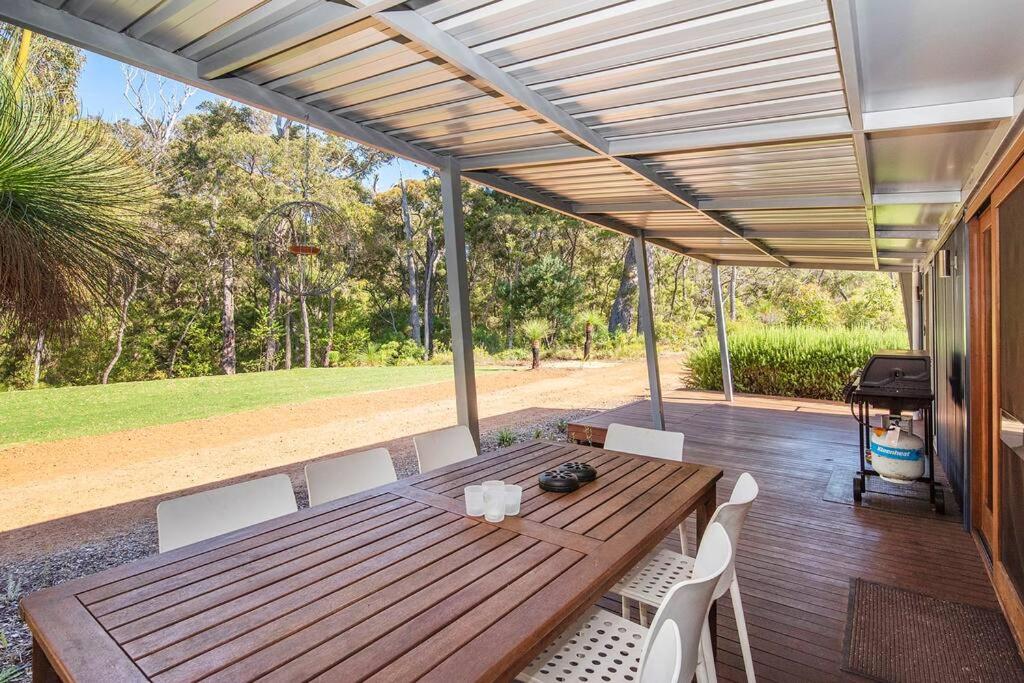 a wooden table and chairs on a deck with a view at Blue Haven Margaret River tranquil bush retreat in Margaret River Town