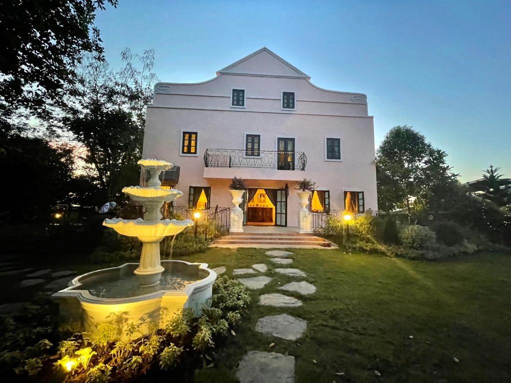 a large white house with a fountain in the yard at Villa Malinee Khao Yai in Ban Tha Chang