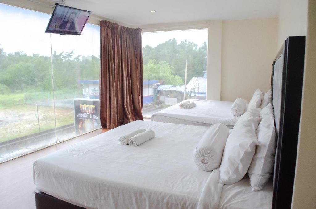 two beds in a room with a large window at M Season Boutique Hotel Sdn Bhd in Sungai Petani