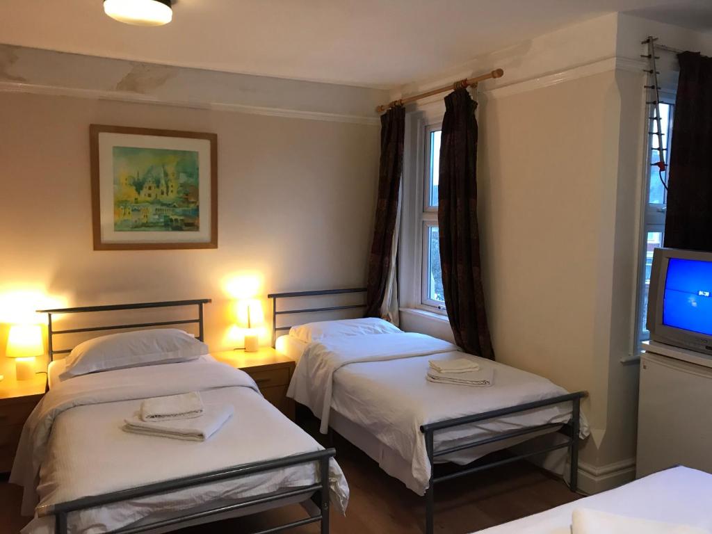 2 Betten in einem Zimmer mit einem TV und 2 Lampen in der Unterkunft Atlas Oxford House in Oxford