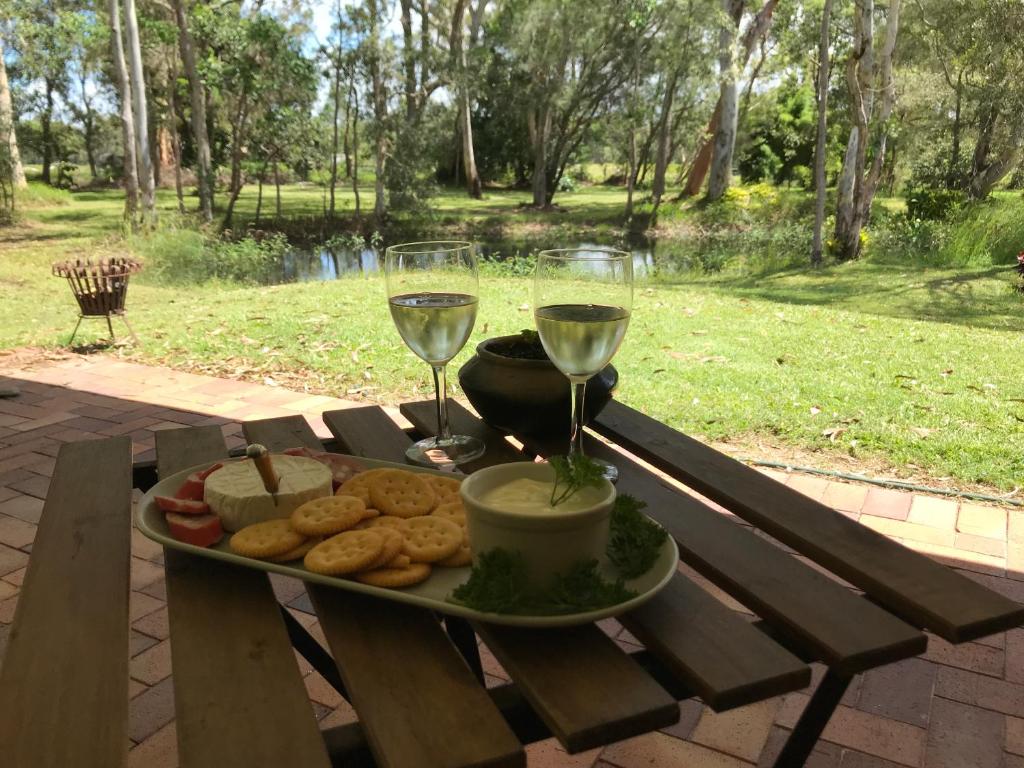 un plato de comida y dos copas de vino en una mesa de picnic en Noosa Lake Weyba en Weyba Downs
