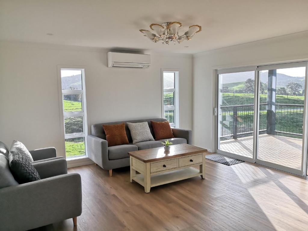 a living room with a couch and a coffee table at Karapiro Retreats holiday house in Cambridge