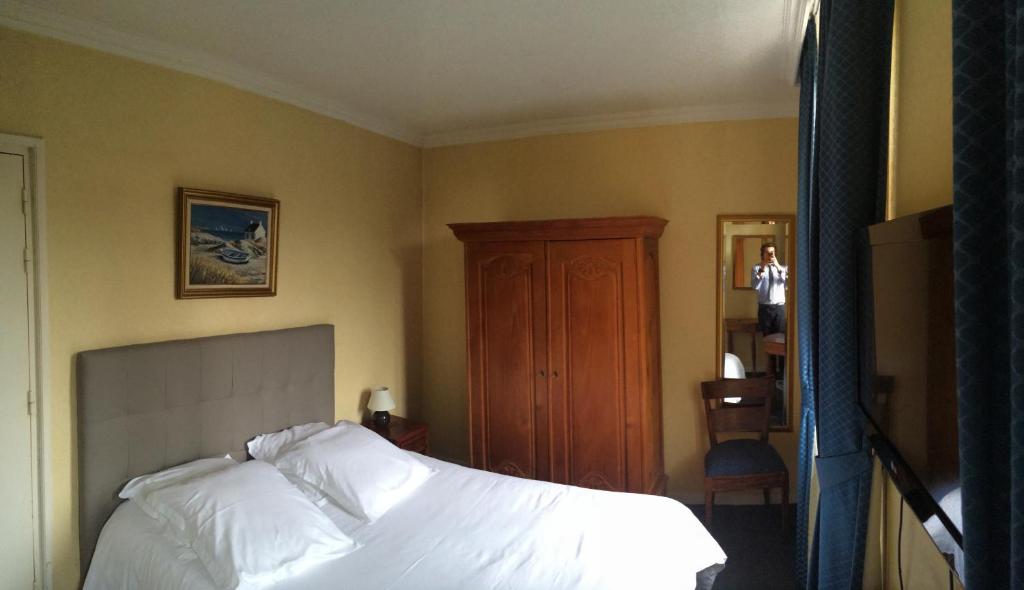 a bedroom with a white bed and a wooden cabinet at Hôtel Saint Alban in Saint-Maur-des-Fossés