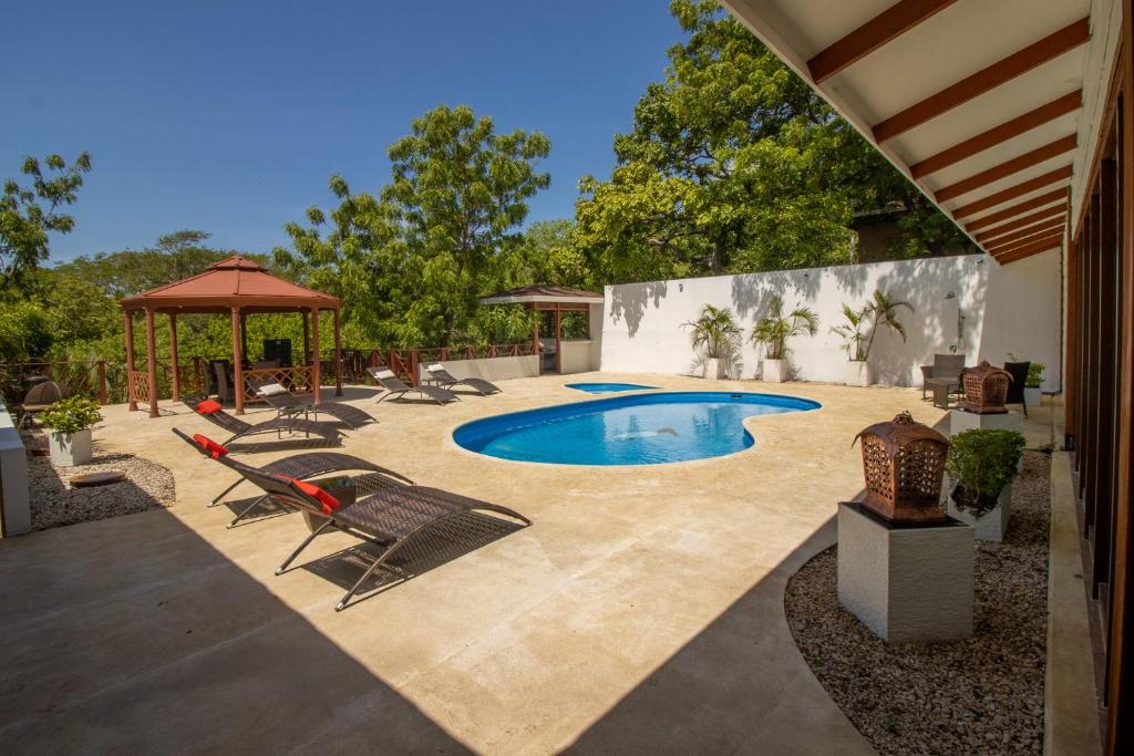 a swimming pool with chairs and a gazebo at Rancho Humo Estancia in Puerto Humo