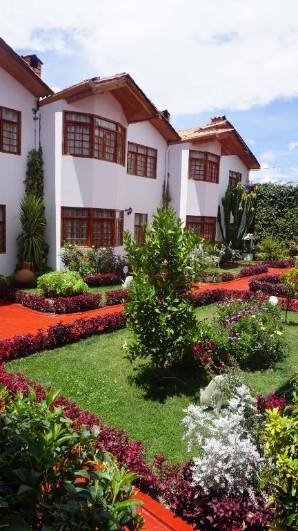 un jardin en face d'un bâtiment fleuri dans l'établissement Hotel & Bungalows Villa Valencia, à Huaraz