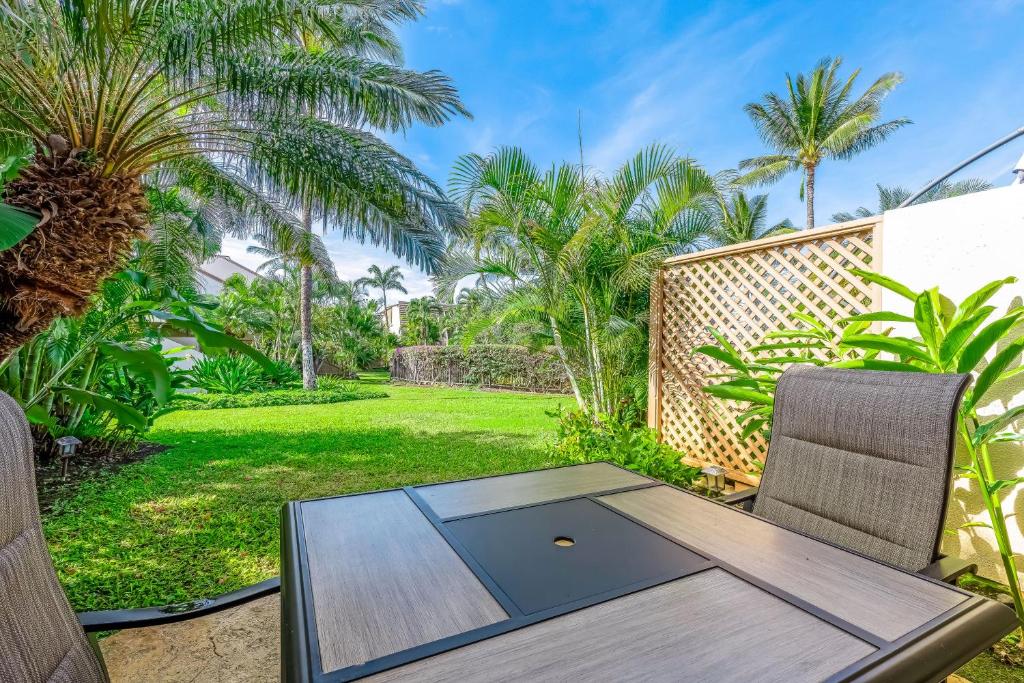 a wooden table and chairs on a patio with palm trees at Maui Kamaole M104 in Wailea