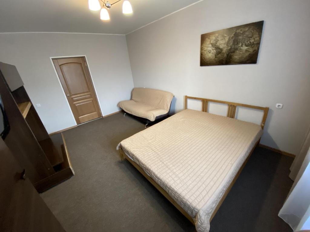 a bedroom with a bed and a chair in it at Dekabrist Apartment at Kirova 16 in Chita
