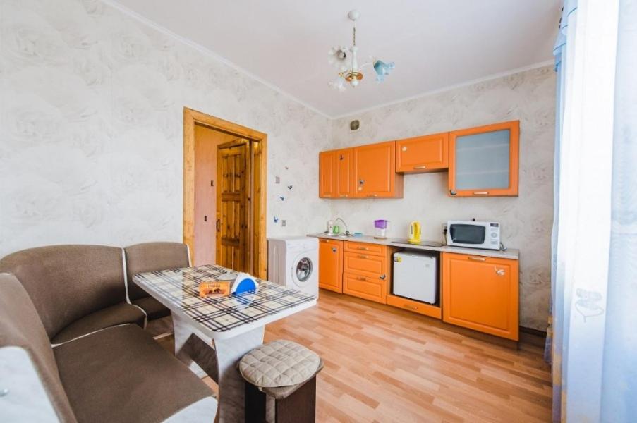 a kitchen with orange cabinets and a table in a room at Dekabrist Apartment on Chkalova 25 in Chita