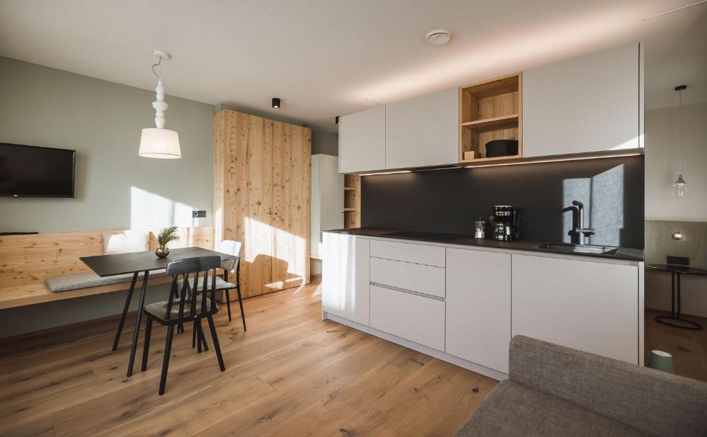 a kitchen with white cabinets and a table with chairs at AHRN Natur Apartment in Lutago