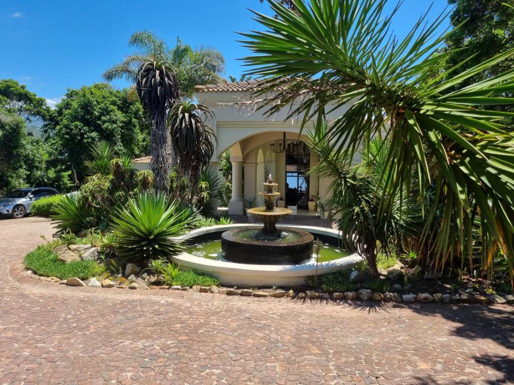 a fountain in front of a house with palm trees at Lodge on Lake in Wilderness