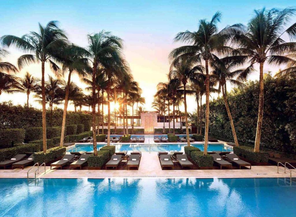 a swimming pool with lounge chairs and palm trees at The Setai, Miami Beach in Miami Beach