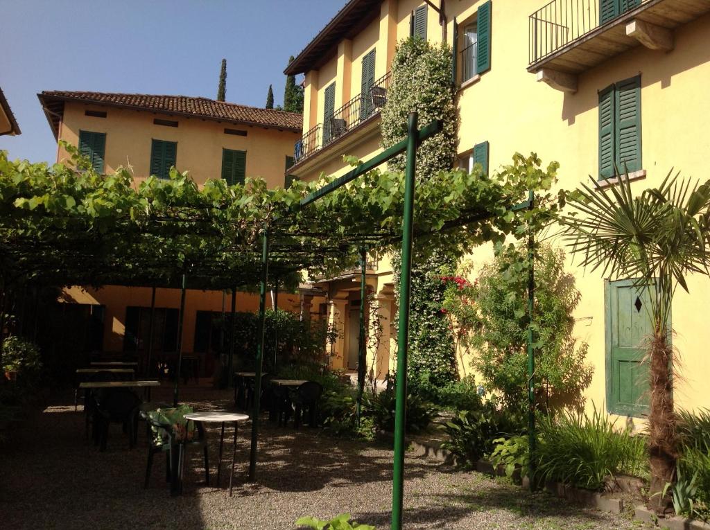 ogród ze stołami i krzesłami oraz budynek w obiekcie Albergo Giardinetto w mieście Bellagio