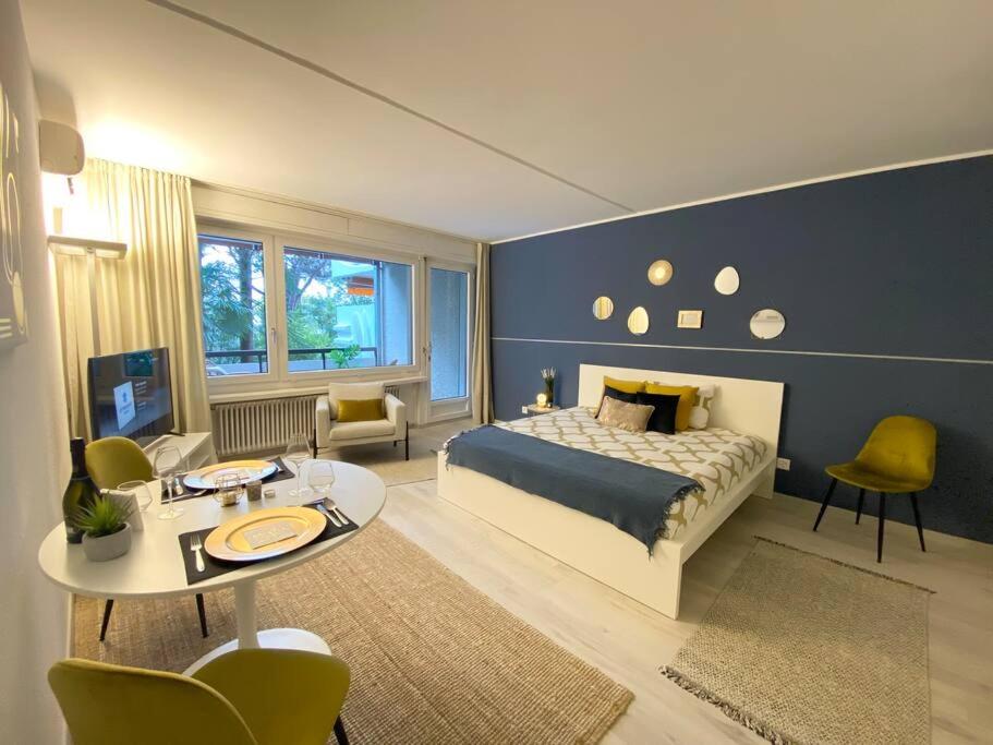 1 dormitorio con 1 cama, mesa y sillas en Luganersee, Pool, Strand, Parkplatz, Suite, en Bissone