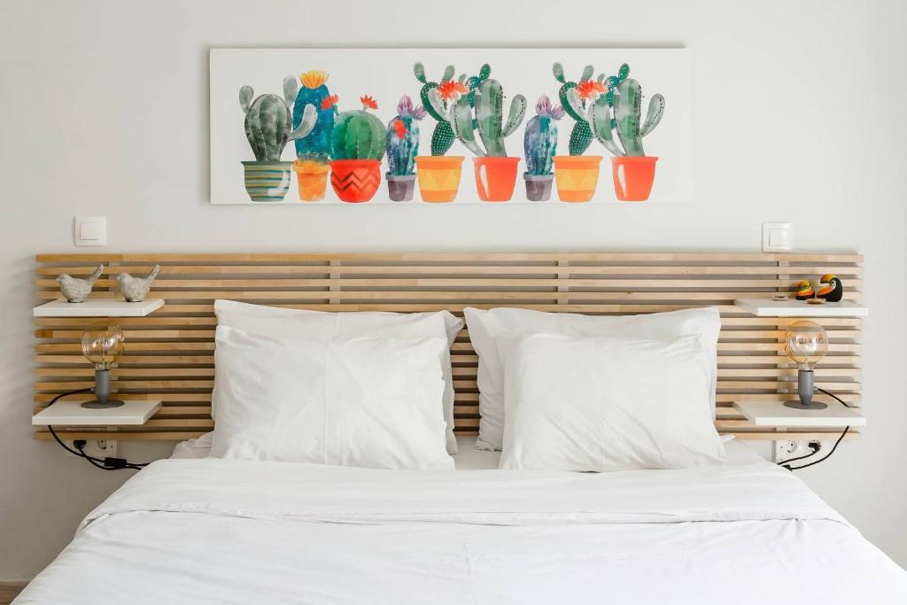 łóżko z białymi poduszkami i drewnianym zagłówkiem z kaktusami w obiekcie Koukaki Studio with a Sunny Balcony, near the Acropolis w Atenach