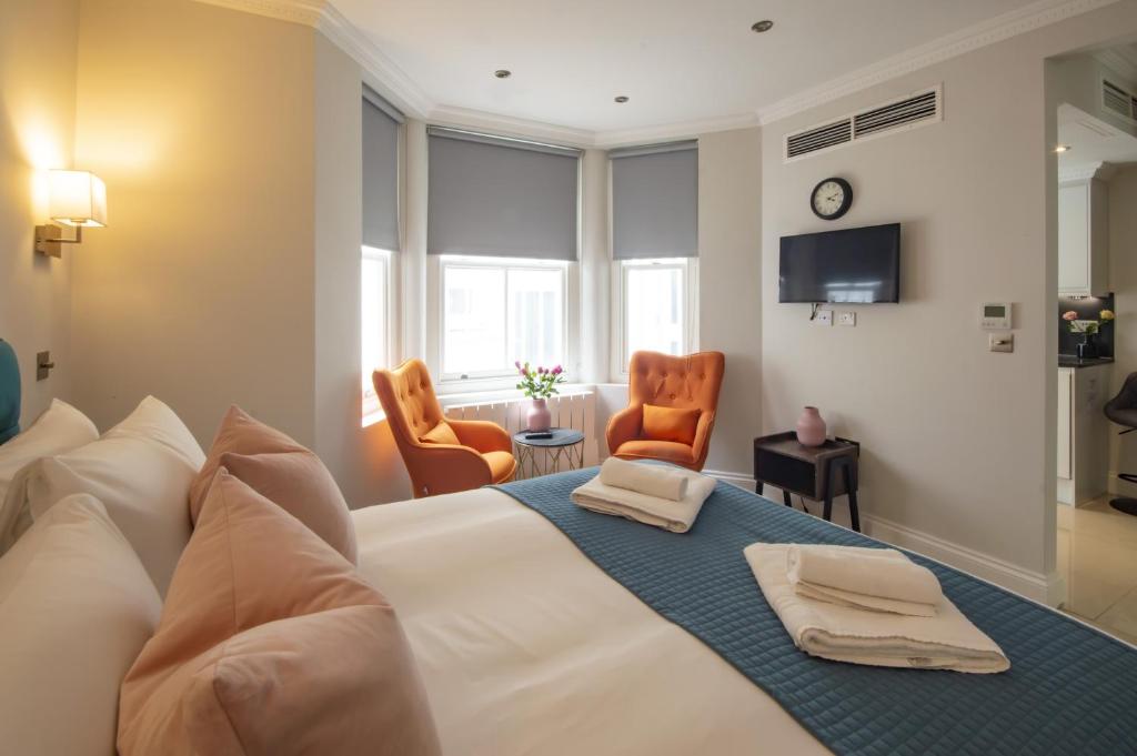 a hotel room with a bed and two chairs at High Street Kensington by Viridian Apartments in London