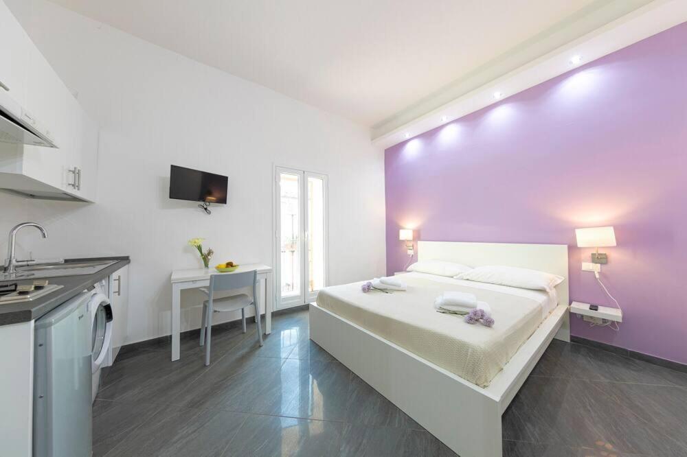 a bedroom with a bed and a purple wall at Maremio in Cefalù