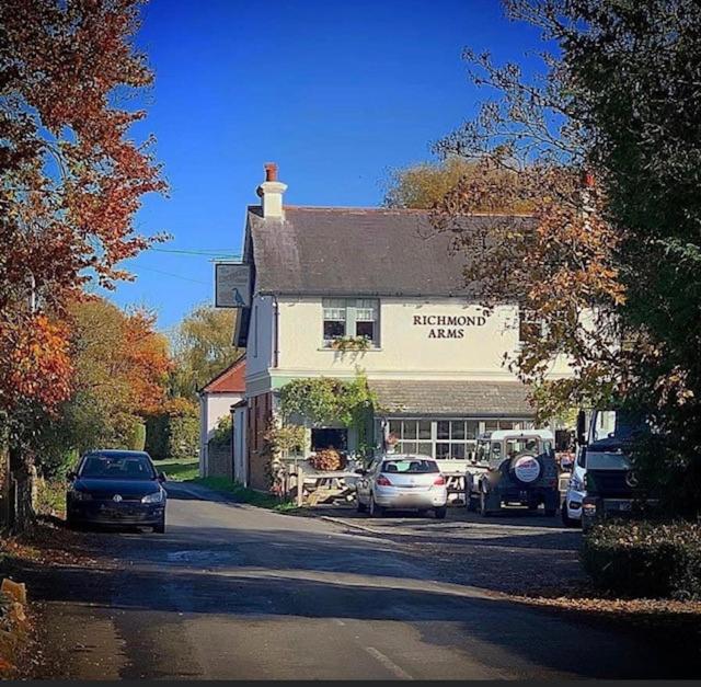 um edifício com carros estacionados em frente em The Richmond Arms Rooms em Funtington