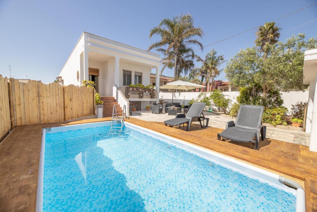 una piscina con dos sillas y una casa en Sun Beach Villa, en Marina di Mancaversa