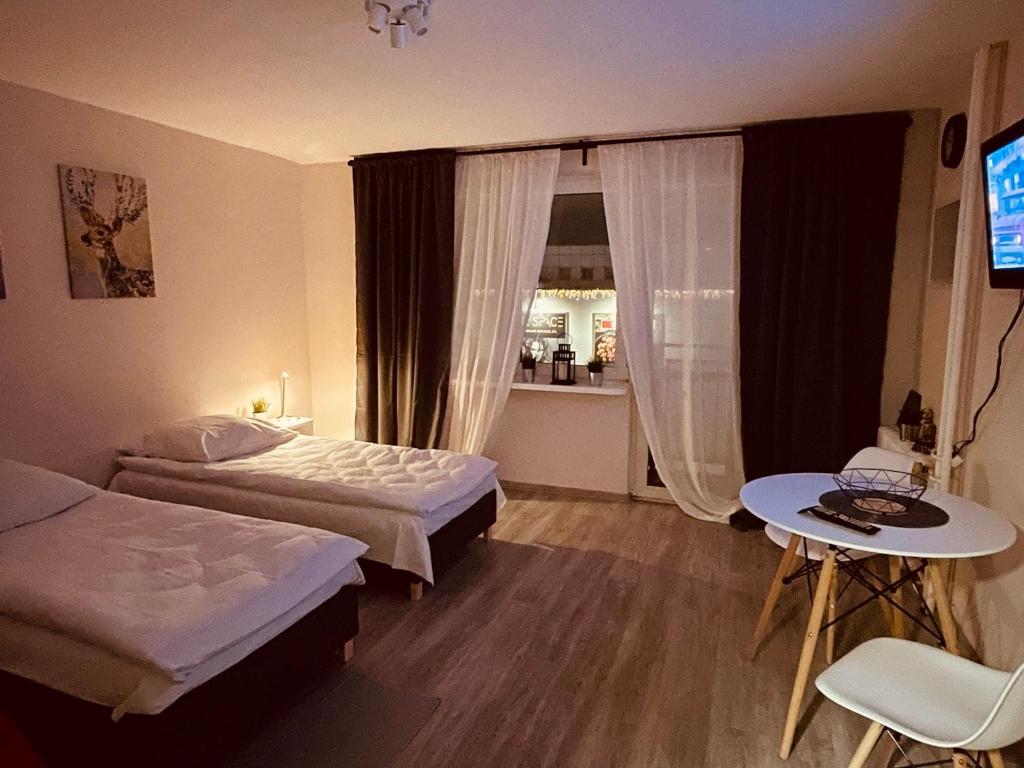 1 dormitorio con 2 camas, mesa y TV en 03 Gdynia Centrum - Apartament Mieszkanie dla 2 os en Gdynia