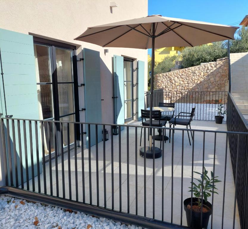 a balcony with a table and an umbrella at DESIGN hotel VERBENICUM in Vrbnik