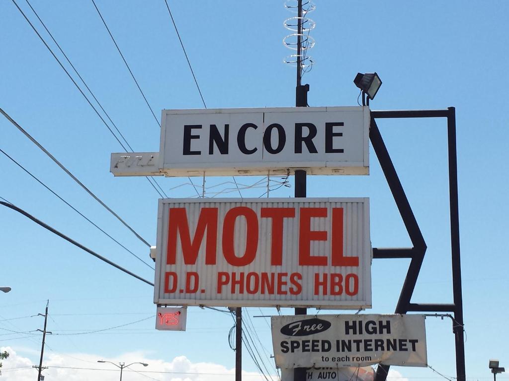 una señal de motel en un poste con algunas señales en Encore Motel, en Farmington