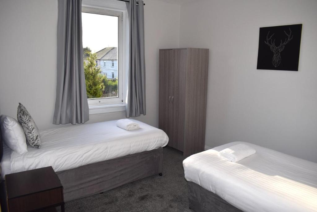 a room with two beds and a window at Kelpies Serviced Apartments - McClean in Falkirk