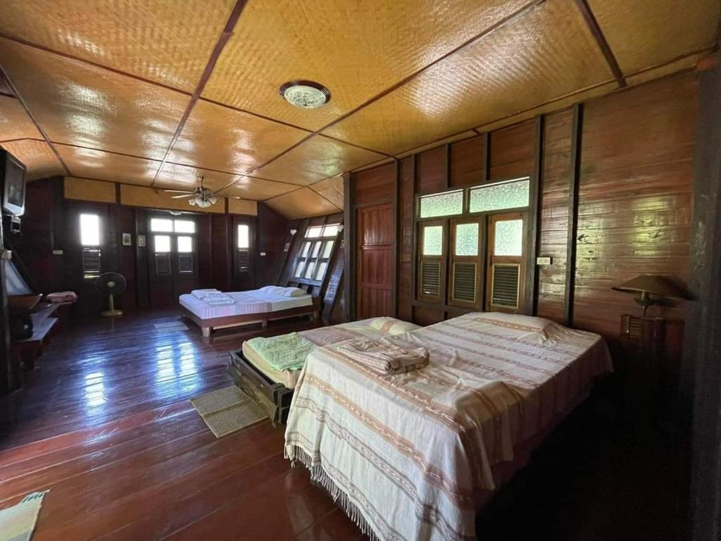 1 dormitorio con 2 camas y suelo de madera en จำค่า ชาเลท์ บ้านพักสวนเกษตร (Jumka Chalet - Home and Farm Stay), en Ban Cham Kha