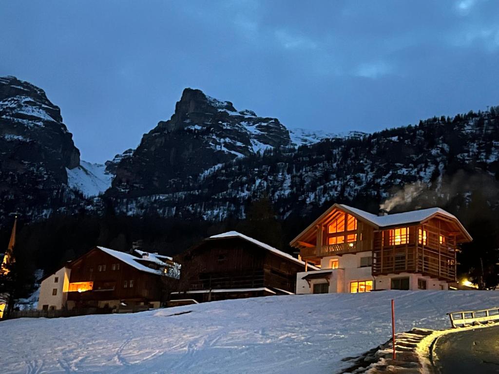 a house on a snowy hill with mountains in the background at Cosy Winter - Luxury Chalet at the foot of the Dolomites in La Villa