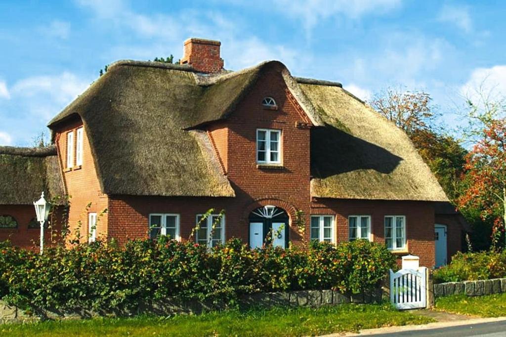 an old brick house with a thatched roof at Holiday Home Witsum - DNS10055-F in Hedehusum