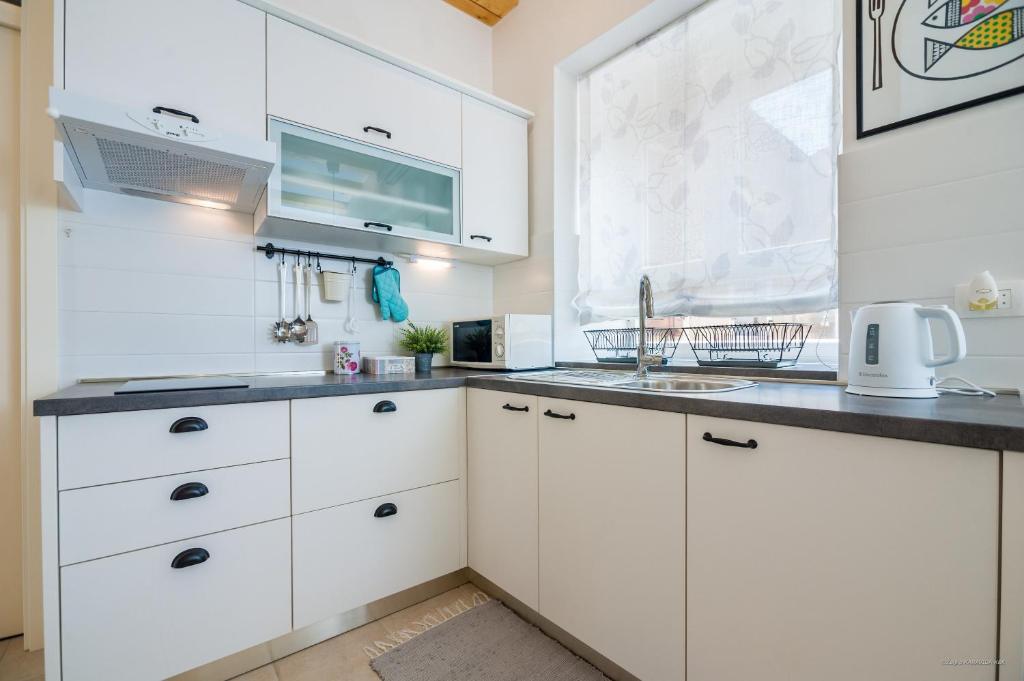 a kitchen with white cabinets and a sink at Aldo Apartments Center in Zadar