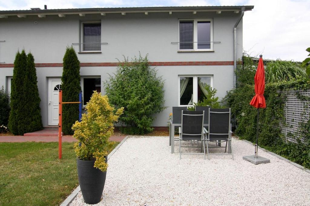 une maison avec une table, des chaises et un parapluie rouge dans l'établissement Apartment, Ribnitz-Damgarten, à Ribnitz-Damgarten