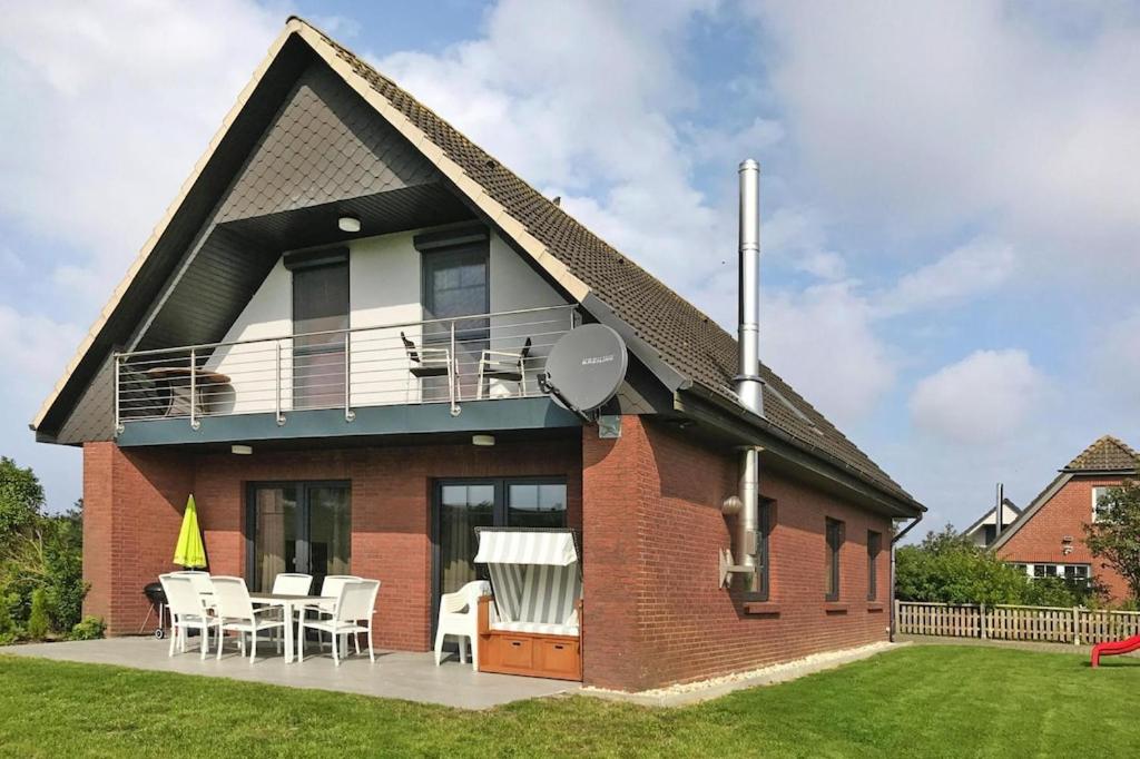a house with a balcony and a table and chairs at Komfortables Ferienhaus in Friedrichskoog-Spitze in Friedrichskoog-Spitz