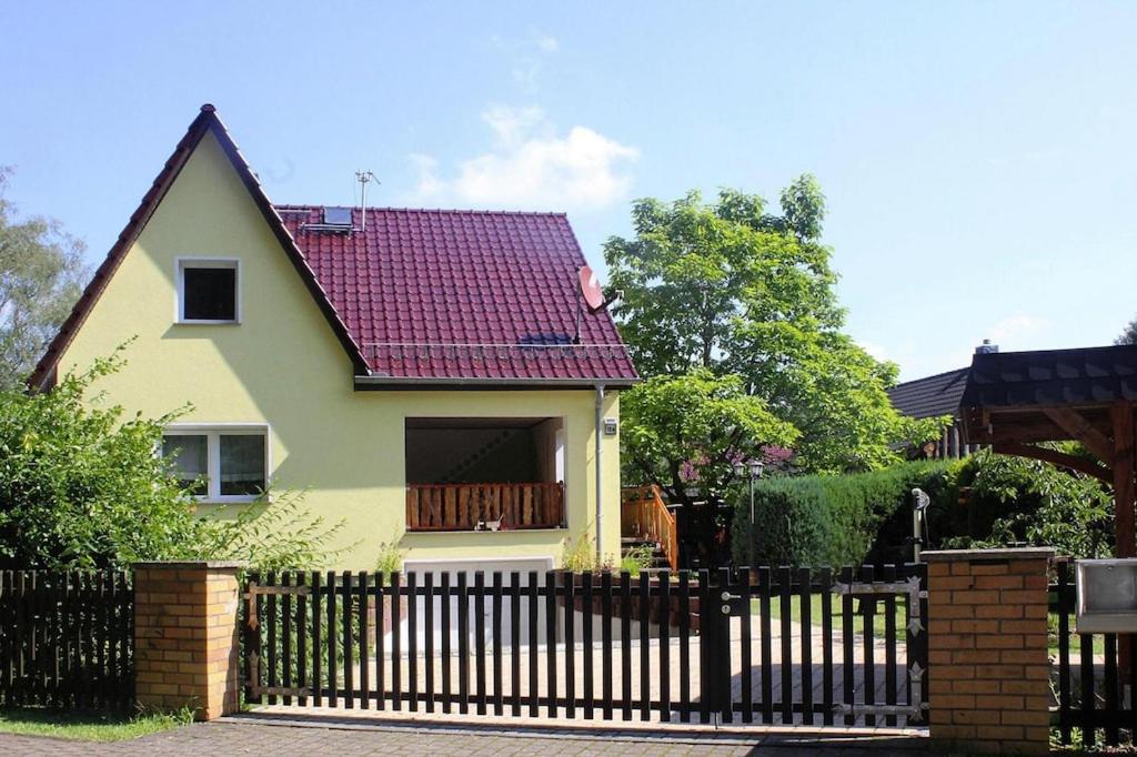 a yellow house with a red roof with a fence at Holiday Home Storkow - DBS05105-F in Storkow