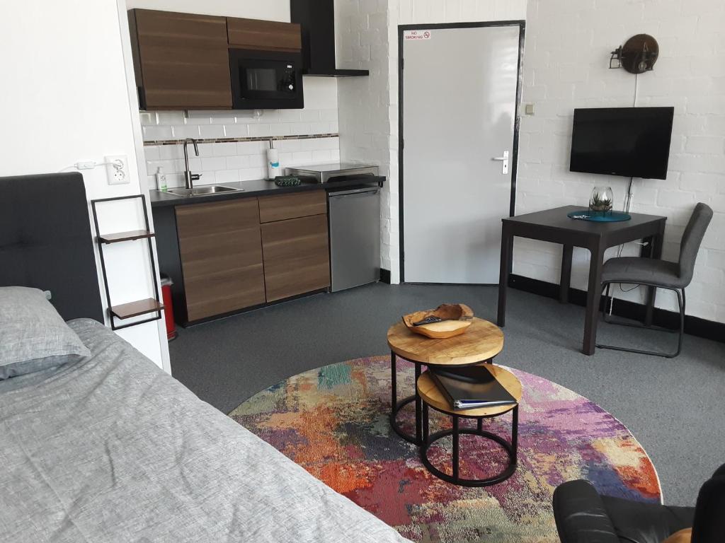Zimmer mit einem Bett und einem Tisch sowie einer Küche in der Unterkunft Le Petite in Sittard