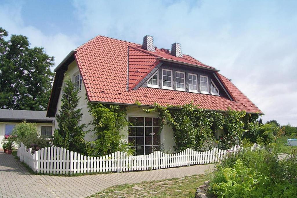 a house with a red roof and a white fence at Apartment, Dallgow-Döberitz in Staaken