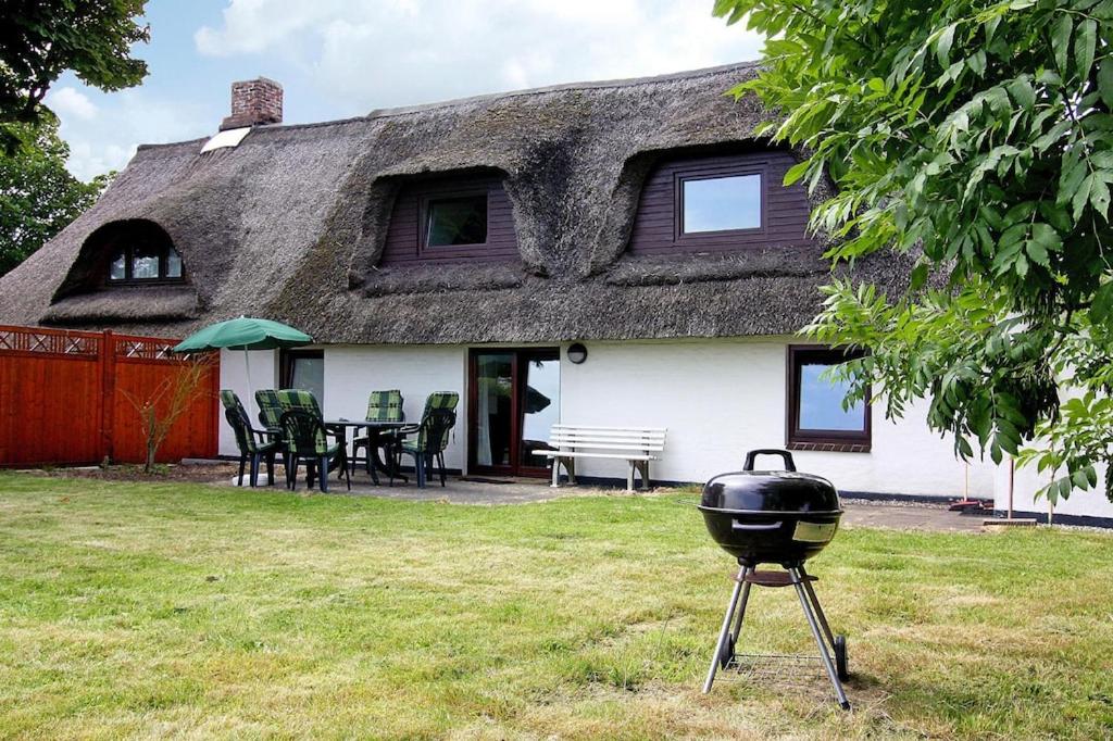 a thatched house with a grill in the yard at Holiday home on the dike, Büsum in Westerdeichstrich