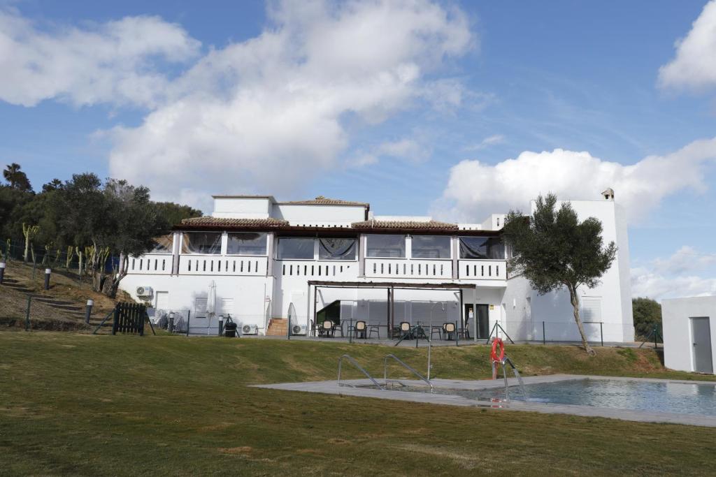 - un bâtiment blanc avec une piscine en face dans l'établissement Hostal Restaurante Benalup Golf, à Benalup-Casas Viejas