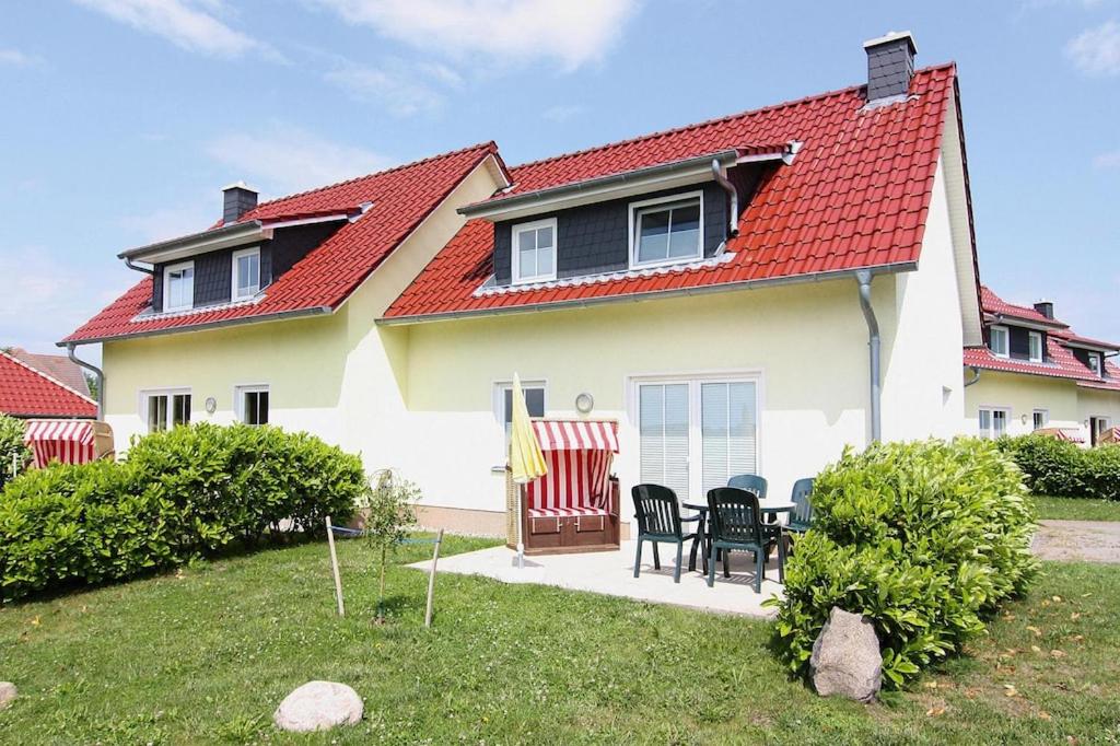 una casa con techo rojo, mesa y sillas en Semi detached house Kuehlungsborn en Kühlungsborn
