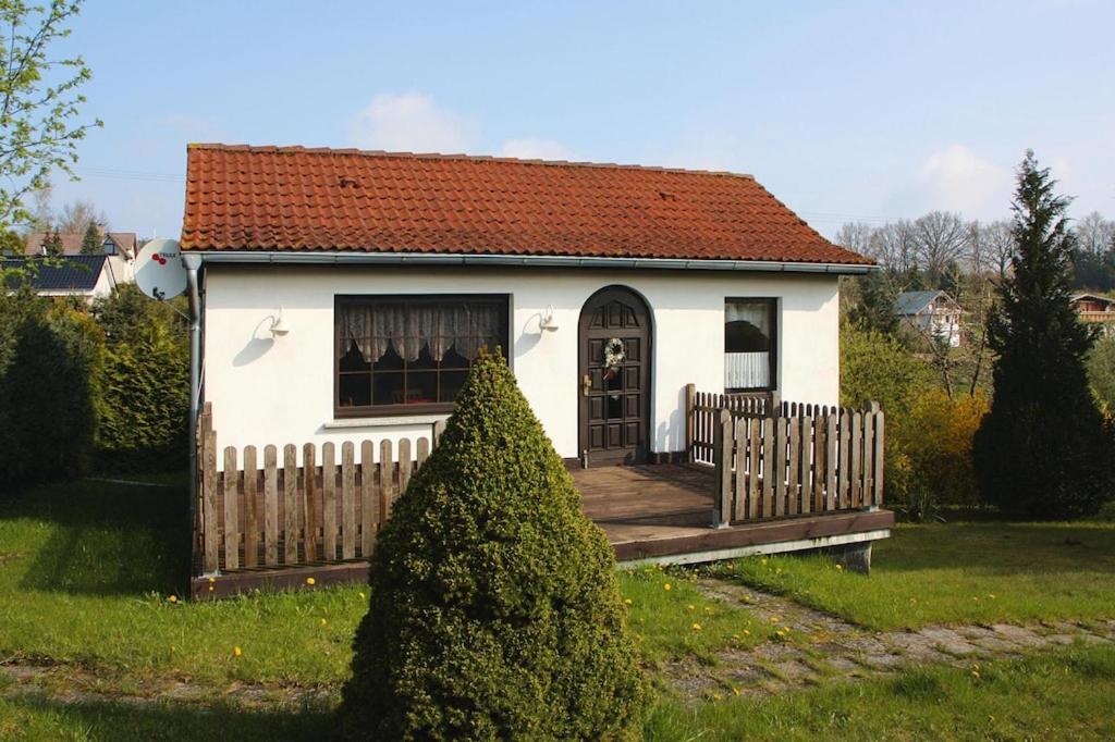 een klein wit huis met een houten hek in een tuin bij Cottage, Dolgen am See in Klein Sprenz
