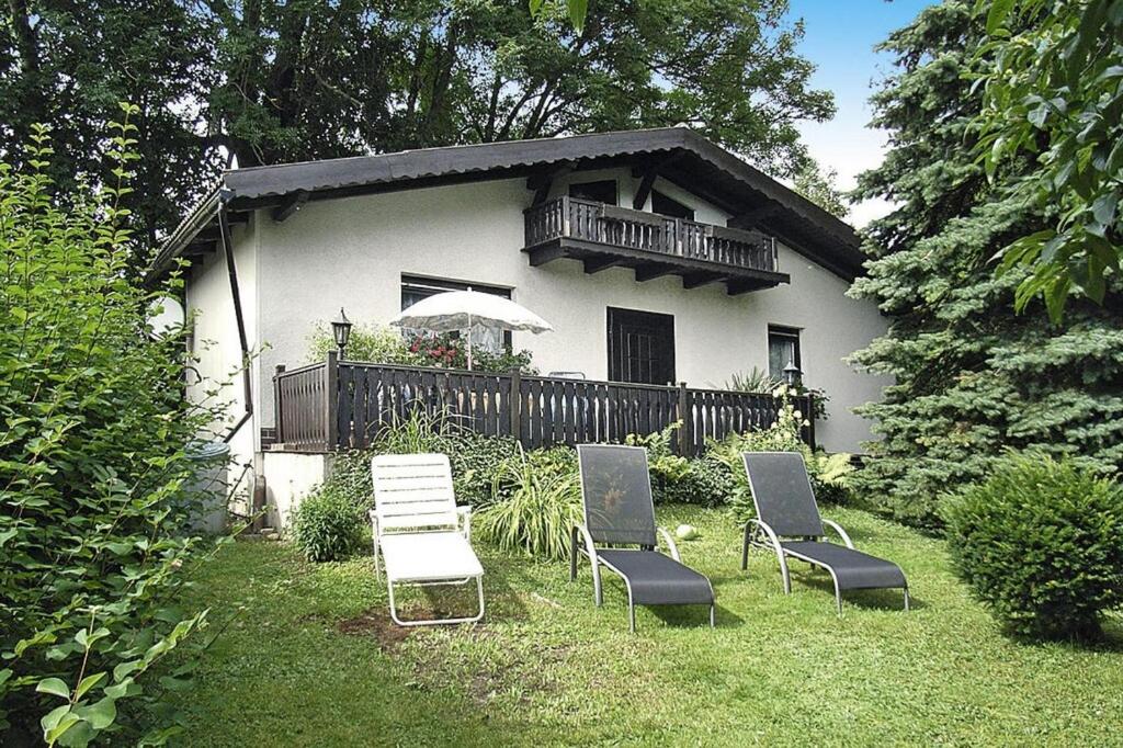 un grupo de sillas sentadas en el césped frente a una casa en Cottage, Jagdhof, en Judenbach